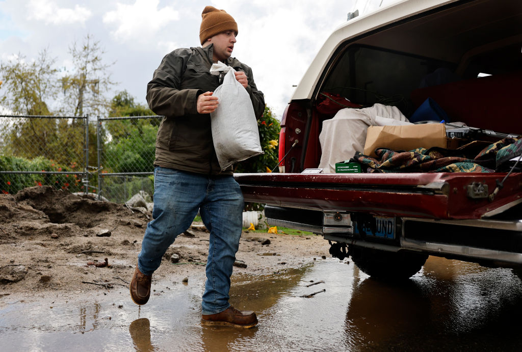 Resident Luis Nelson loads a sandbag into his truck in preparation for heavy rains from an atmospheric river storm on March 12, 2025 in Sierra Madre, California. Mandatory evacuations are in place in some areas of Sierra Madre which experienced mudflows in the Eaton Fire burn scar during heavy rains last month. (Photo by Mario Tama/Getty I